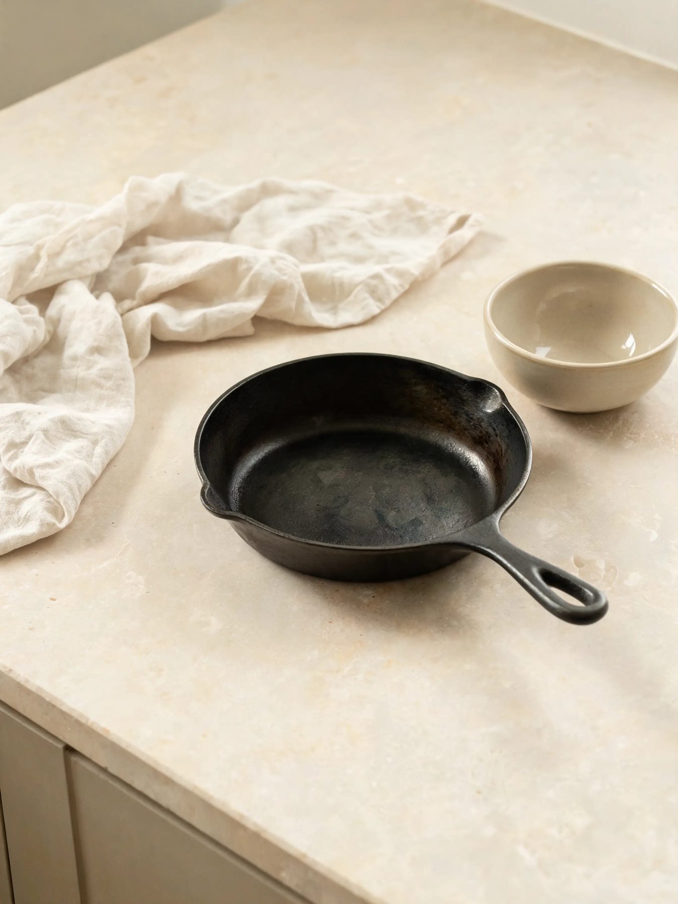 Seasoned skillet and glazed stoneware bowl on a limestone counter